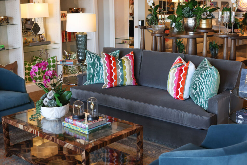 gray velvet sofa and bright patterned pillows staged living room inspiration in reserve amarillo. interior design, home decor and furniture store in wolflin village in amarillo from 6th collective