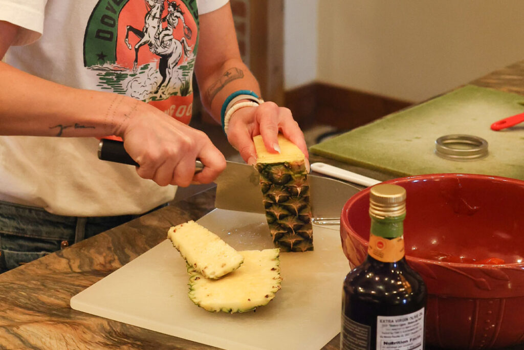 Dove Creek Equine Rescue kitchen volunteer cutting pineapple for weeknight menu